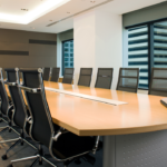 Why Would I Want to Use White Glove Moving? 2 Modern conference room featuring a large wooden table surrounded by ergonomic black chairs, with large windows showcasing a city skyline. A laptop is placed on the table, creating an ideal setting for business meetings and presentations.