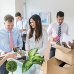 Renting vs. Buying Packing Supplies: Tips for Minimizing Packing Material Costs 3 Group of diverse professionals collaborating in a bright office space, discussing ideas and unpacking office supplies from boxes, showcasing teamwork and a productive work environment.